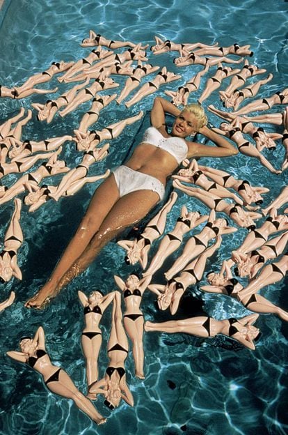 Jayne Mansfield flota en una piscina de California en 1957. Eso que la rodean no son muñecas de sí misma, no, es todavía mejor: son botellas con su forma.