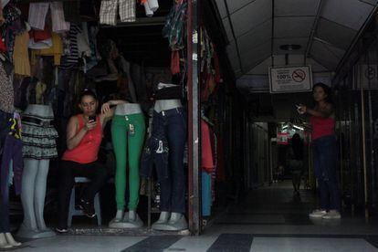 Dos comerciantes permanecen en sus tiendas a oscuras en San Cristóbal, al oeste del país, este martes. Algunas zonas de otro estado occidental, Zulia acumulan 31 horas seguidas sin electricidad desde el apagón del lunes.