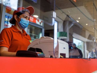 Una empleada de la cadena de pizzerias Telepizza posa tras una mampara de protección en uno de sus establecimientos en Alcobendas
 