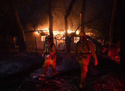 Los bomberos se alejan de una casa en llamas después de descubrir líneas eléctricas caídas, en Carpinteria, California, el 10 de diciembre. El incendio amenaza ahora la ciudad de Santa Bárbara.