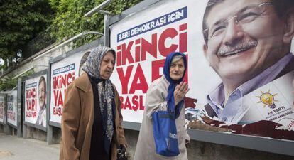 Dos mujeres caminan junto a carteles electorales con la imagen del primer ministro turco, Ahmet Davutoglu, en Estambul.
