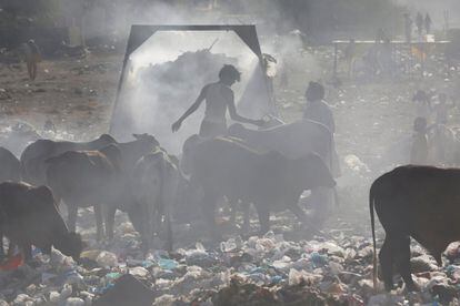 Hombre y niños entre el polvo de un vertedero en Karachi, Pakistán, mientras buscan objetos que puedan reciclar.