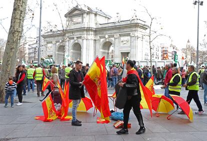 Un vendedor ambulante vende paraguas y banderas de España durante la manifestación de agricultores, este miércoles en Madrid. 