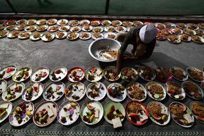 Un indio de religión musulmana distribuye comida en platos para el iftar, comida nocturna con la que se rompe el ayuno, en el primer día del mes de Ramadán en el Burah Majid en Guwahati, el 17 de mayo de 2018.