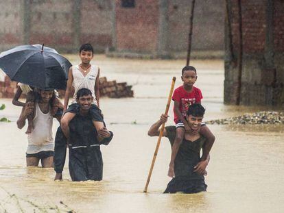 Varios nepalíes huyen de sus casas inundadas en Ramgadhwa, en Nepal, este domingo.