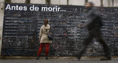Una mujer escribe su deseo en el muro 'Antes de morir quiero...'.