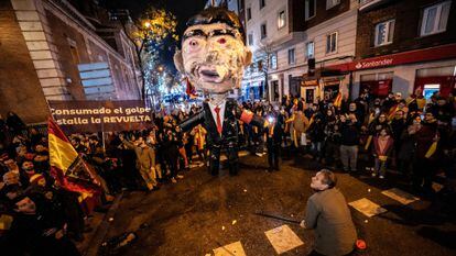 Un hombre se dispone a golpear un muñeco con la figura de Pedro Sánchez en la protesta cerca de la calle de Ferraz, en Madrid, en Nochevieja.