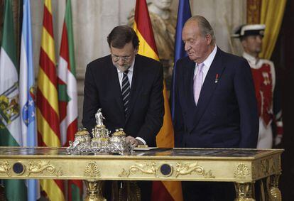 El presidente del Gobierno, Mariano Rajoy (i), junto al rey Juan Carlos, durante la firma de la ley de abdicación.