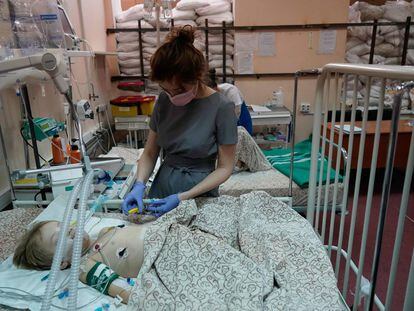 La enfermera Vladislava Filonenko atiende a Belegay, de 5 años, en una habitación protegida por sacos de arena en el Hospital Clínico Infantil Regional de Zaporizhzhia, el martes.