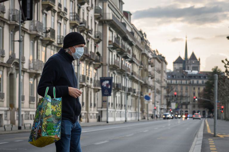 Un hombre con mascarilla cruza la calle en Ginebra, este viernes, cuando el Gobierno suizo endureció aún más las medidas contra el coronavirus.