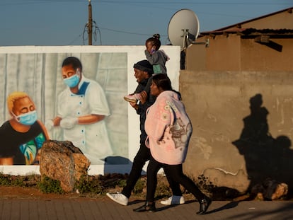 Una familia pasa junto a un mural que promueve la vacunación contra la covid-19 en el municipio de Duduza, al este de Johannesburgo, Sudáfrica, en junio de 2021.