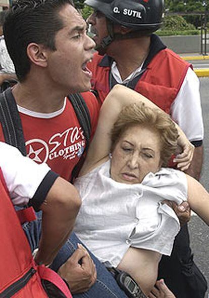 Un hombre lleva en brazos a una de las personas heridas en el tiroteo contra una concentración anti-chavista.