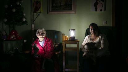 Dos mujeres iluminan con linternas el salón de su casa, en Barcelona en 2020.