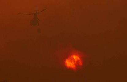 Un helicòpter dels serveis d'extinció treballa per extingir les flames que avancen cap a la localitat de Constante, Lugo.