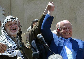 Arafat y Qurei (derecha) saludan desde la sede de la Presidencia palestina en Ramala.