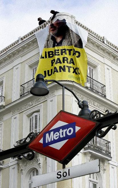 Miembros de Greenpeace España cuelgan la pancarta con la imagen de su presidente con la frase <i>Libertad para Juantxo</i>, en uno de los edificios de la Puerta del Sol.
