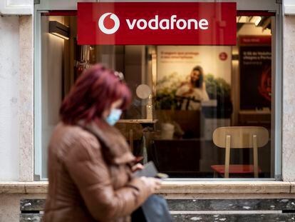 Una mujer consulta su móvil frente a una tienda de Vodafone en Caldas da Rainha (Portugal).