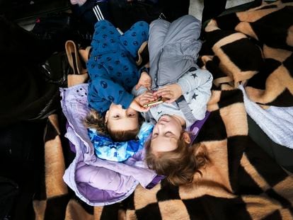 Dos niñas ucranias refugiadas juegan con un móvil en un centro comercial polaco, donde junto a otros compatriotas, son atendidos y asesorados tras pasar la frontera, el 4 de marzo en Mlyny, Polonia.