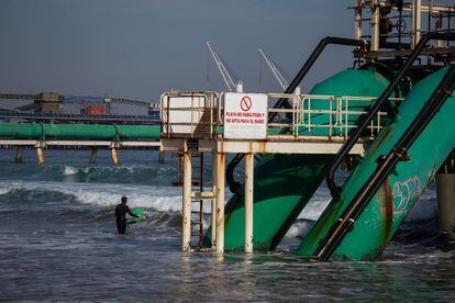 Un surfista entra al mar en el puerto de Ventanas en la comuna de Puchuncaví. La ministra de Medio Ambiente, Maisa Rojas, explicó que la iniciativa de cerrar la sede de Ventanas se trata de una señal evidente de apuesta por la sostenibilidad. 