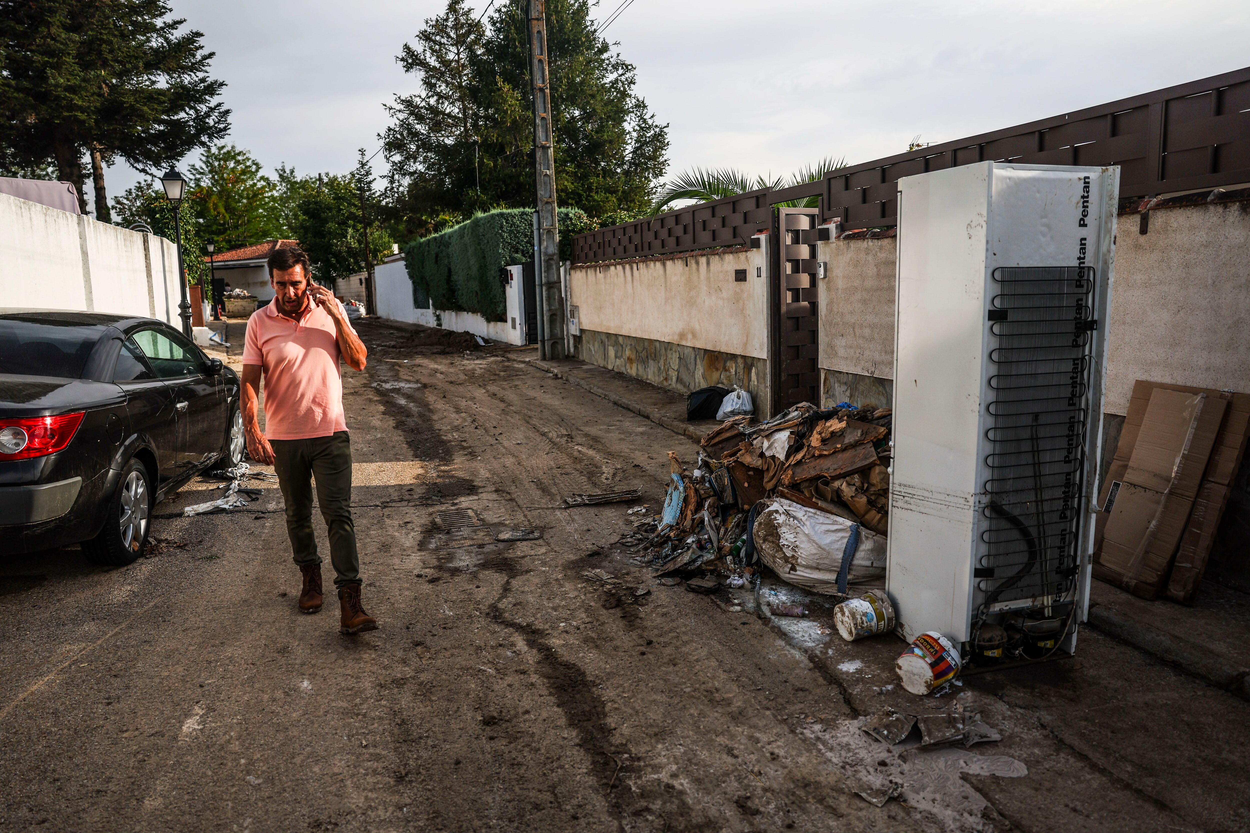 Mariano Núñez, alcalde de Villamanta (Toledo), habla por teléfono mientras camina por una de las calles convertidas en un lodazal.