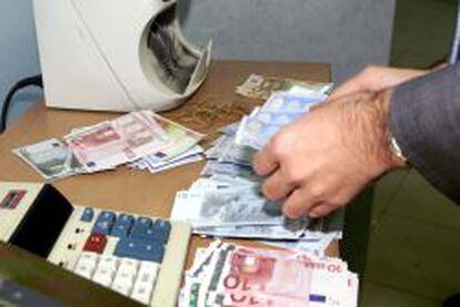 Una m&aacute;quina cuenta billetes de euros en una sucursal bancaria. 