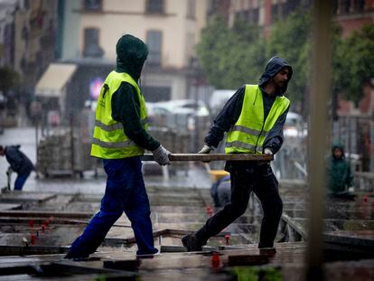 Un grupo de operarios durante el montaje de palcos de Semana Santa en Sevilla. PACO PUENTES (EL PAÍS).