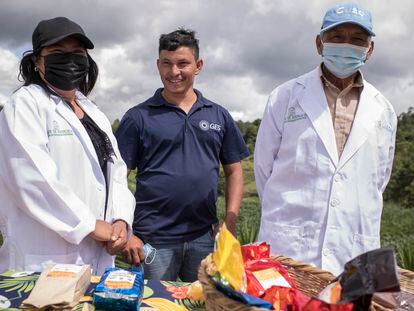 José Luis, un agricultor que fue repatriado a Honduras tras ser detenido en Estados Unidos, junto a dos expositores en una muestra gastronómica y de agricultura en Cerro Verde, Honduras.