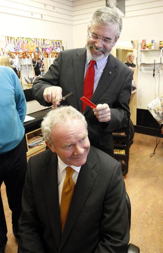 El presidente de Sinn Fein, Gerry Adams, bromea cortar el pelo al candidato de su partido Martin McGuinness.