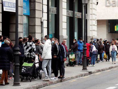 Ciudadanos esperando recibir comida de un banco de alimentos en el centro de Valencia.