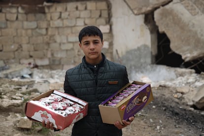 Hussein Mutawa, de 12 años, frente a un edificio destruido en su pueblo de Sarmin, en el campo de Idlib, mientras deambula por las inseguras calles de la ciudad para vender galletas. Hussein dejó la escuela temprano y comenzó este trabajo para ayudar a su madre y sus cinco hermanas.