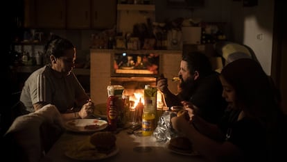 Rocío y su marido Jesús, junto a Jonny, el hijo menor, cenan en su domicilio de la Cañada Real a la luz la lumbre.