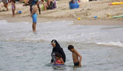 Una mujer en burkini con sus hijos en la playa de Marsella.