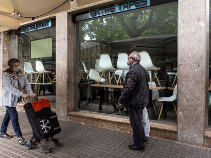 Dos ciudadanos pasan a finales de abril de 2020 delante de un restaurante cerrado por el estado de alarma sanitaria.