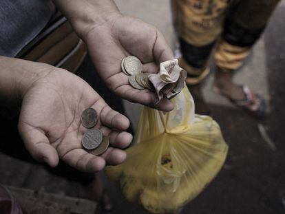 Un cliente sostiene billetes y monedas en un mercado de comida en Riohacha (Colombia).