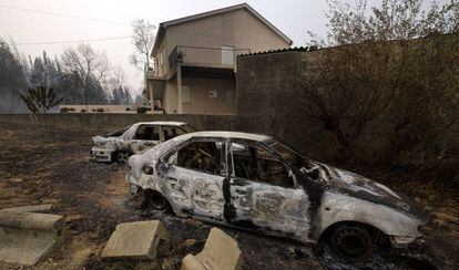 Coches quemados cerca de una vivienda en Penacova, en el norte de Portugal, este lunes.