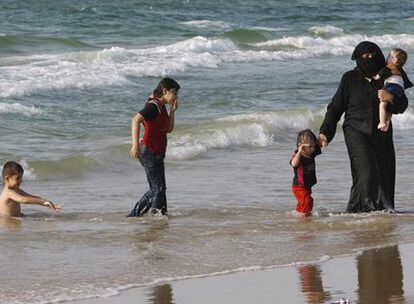 Una palestina completamente cubierta pasea con sus hijos por la playa de Jan Yunis, al sur de la franja de Gaza.