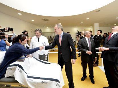 Alberto Fabra saluda a una mujer en la sala de rehabilitaci&oacute;n y Alfonso Alonso mira al techo en la visita al hospital de Ll&iacute;ria.