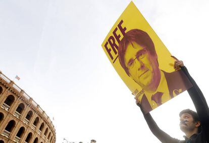 Un joven con la boca precintada lleva una pancarta del expresidente de la Generalitat Carles Puigdemont, en la manifestación del 25 de abril en conmemoración de la batalla de Almansa en Valencia.