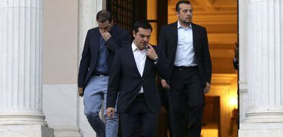 El primer ministro griego, Alexis Tsipras, flanqueado por el ministro de  Presidencia Nikos Pappas (derecha) y el portavoz Gabriel Sakelaridis, abandona sus oficinas para visitar al presidente Prokopis Pavlopoulos, ayer en Atenas.
