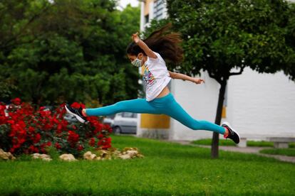 Una niña protegida con mascarilla salta en una calle en Córdoba.