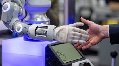 Un hombre tiende la mano a un robot.