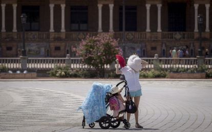 Una turista asiática acompañada de dos niños pequeños intenta aliviar el calor refrescándose con un abanico en la Plaza de España de Sevilla.