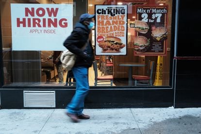 Una persona camina junto a un cartel que anuncia empleo en un restaurante de comida rápida en Nueva York.