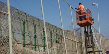 Dos operarios reparan un fragmento de valla arrancado en Melilla.