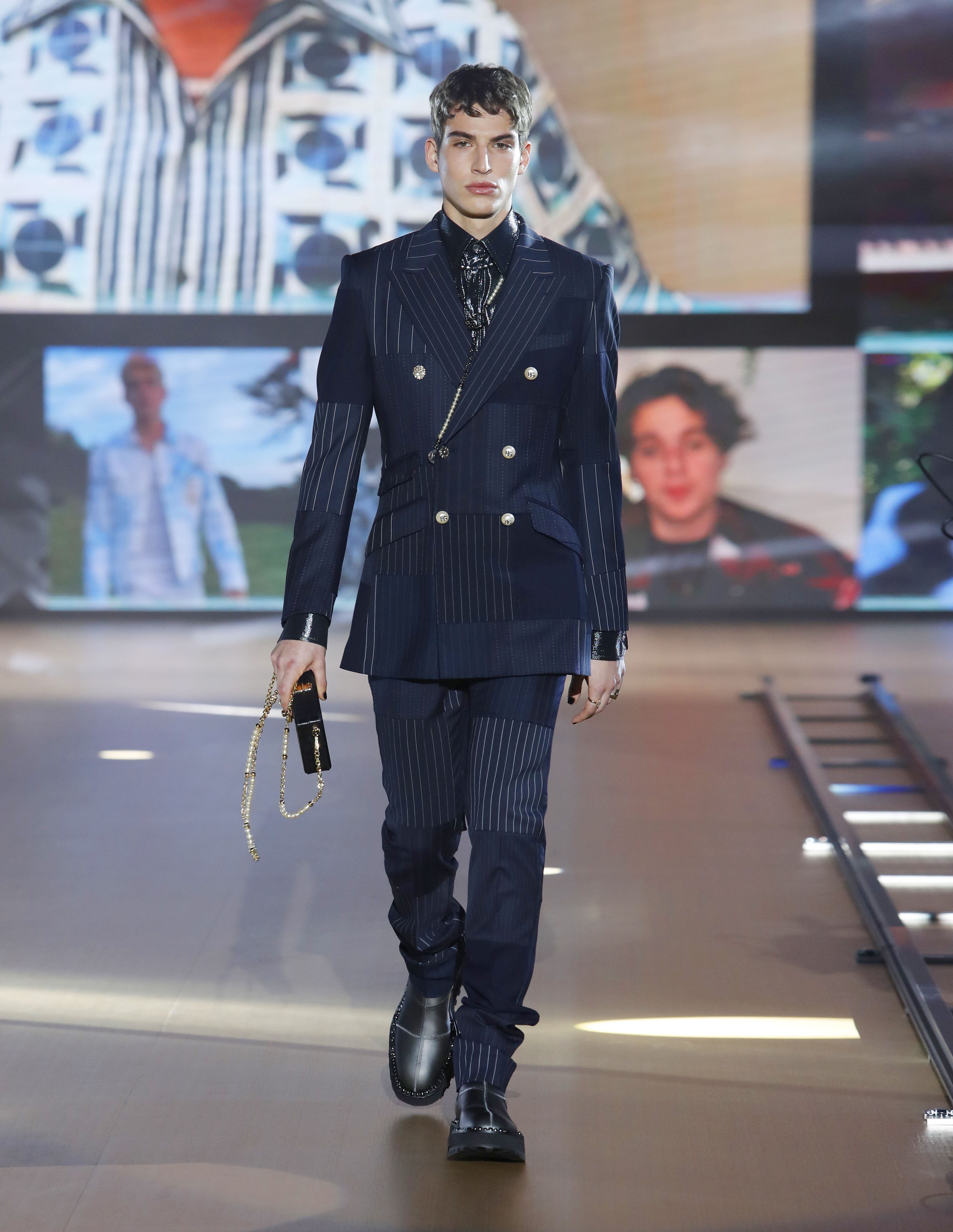 Un traje de chaqueta cruzada con 'patchwork' de tejidos lisos y de raya diplomática abre el desfile otoño/invierno 2021 de Dolce&Gabbana.