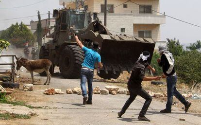 Palestinos lanzan piedras a un bulldozer en la villa de Kafr Qaddum, cerca de Nablus, en Cisjordania.