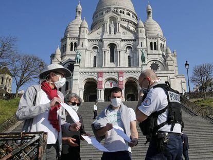 Un policía francés revisa los permisos de un grupo de personas en el barrio de Montmartre