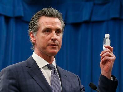 El gobernador de California, Gavin Newsom, muestra un bote de gel desinfectante en una conferencia de prensa, este miércoles en Sacramento.