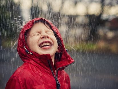 Un niño disfruta con entusiasmo de la lluvia.