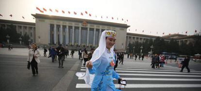 Una delegada de una minoría étnica cruza corriendo un paso de cebra tras asistir a una sesión plenaria de la Conferencia Consultiva Política del Pueblo Chino en Pekín.